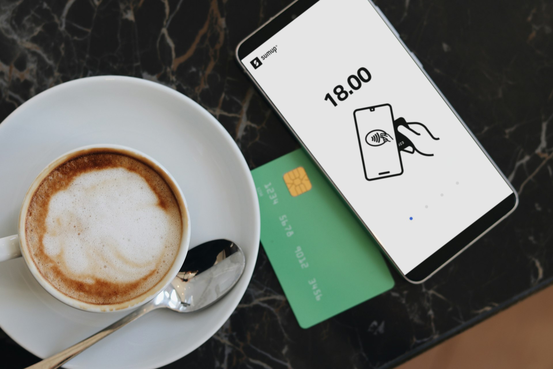 A cup of coffee on a saucer next to a credit card